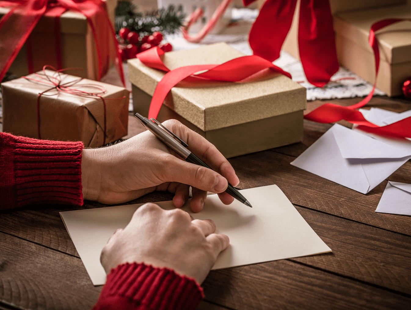 Writing holiday card with gifts nearby