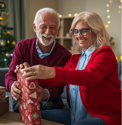 Elderly couple happily opening Christmas gift.