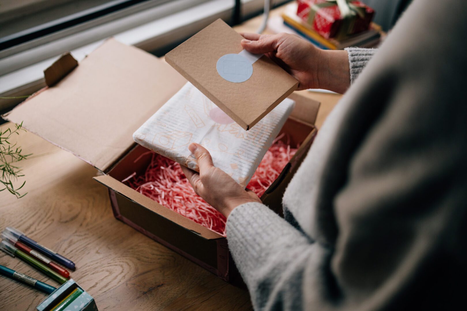 Person unpacking gift box on wooden table.