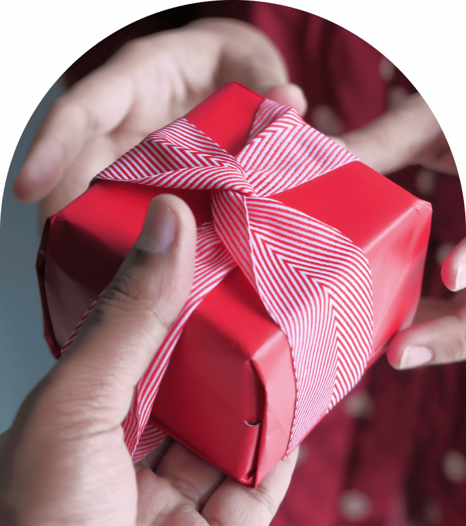 Hands exchanging a red wrapped gift box.
