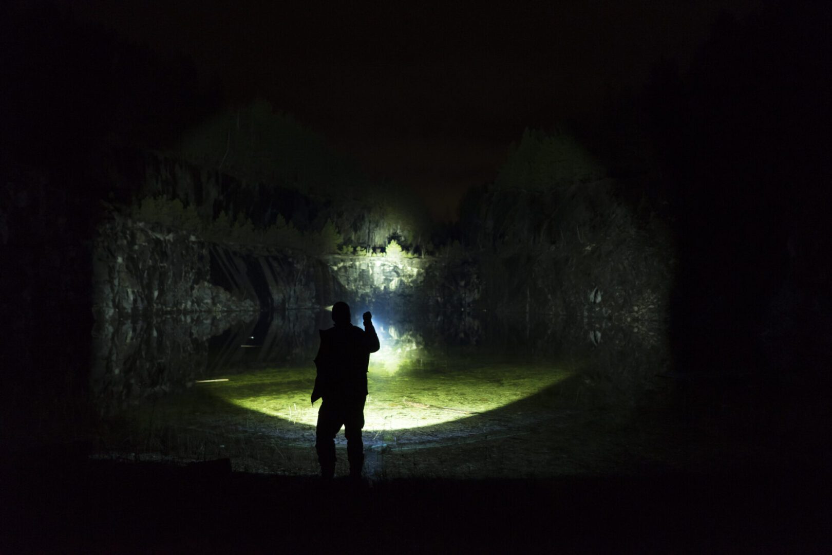 Silhouette of person with flashlight at night.