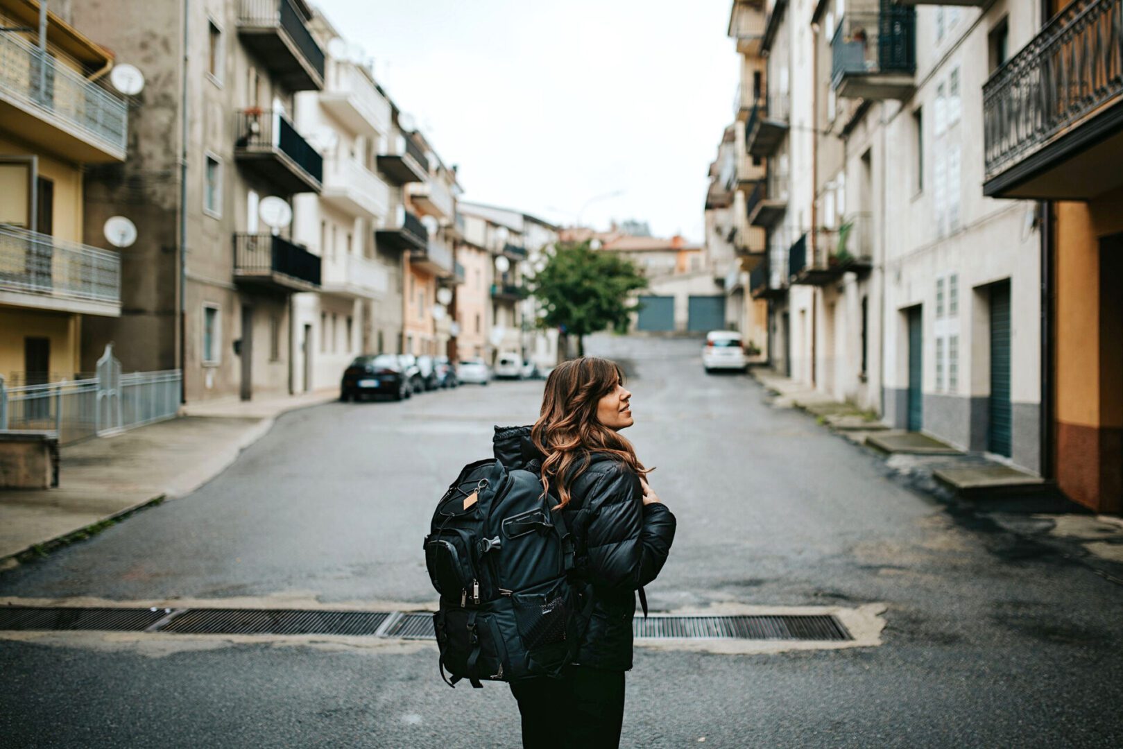 Traveler with backpack walking down urban street.