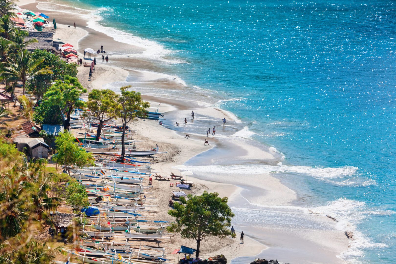 Beach with boats and people enjoying shoreline.