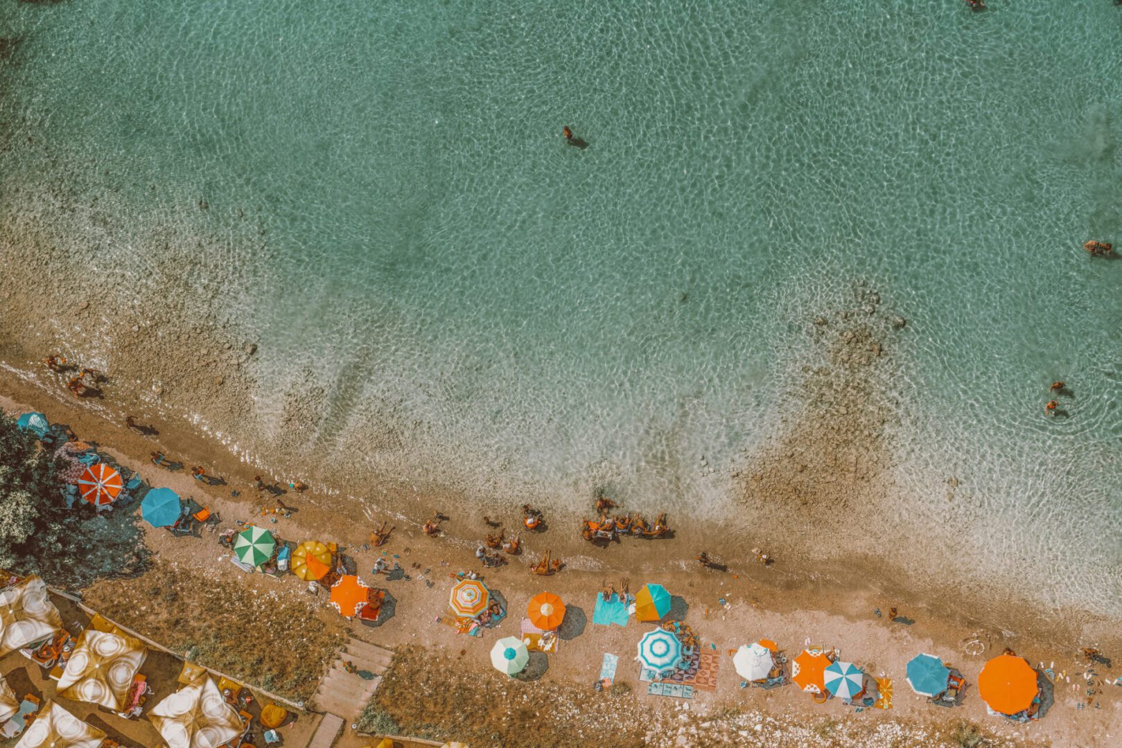 Aerial view of beach with colorful umbrellas.