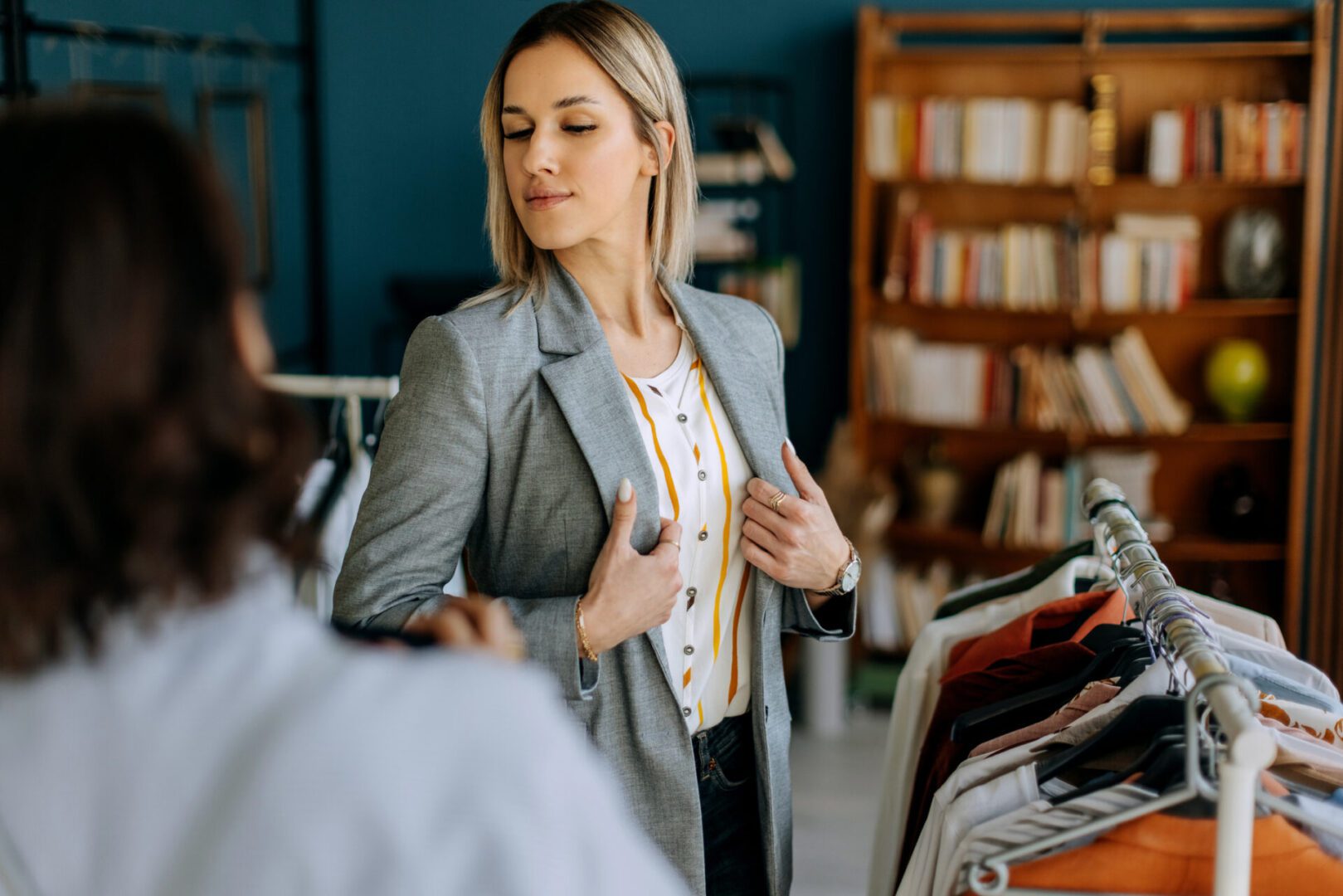 Woman trying on a grey blazer.
