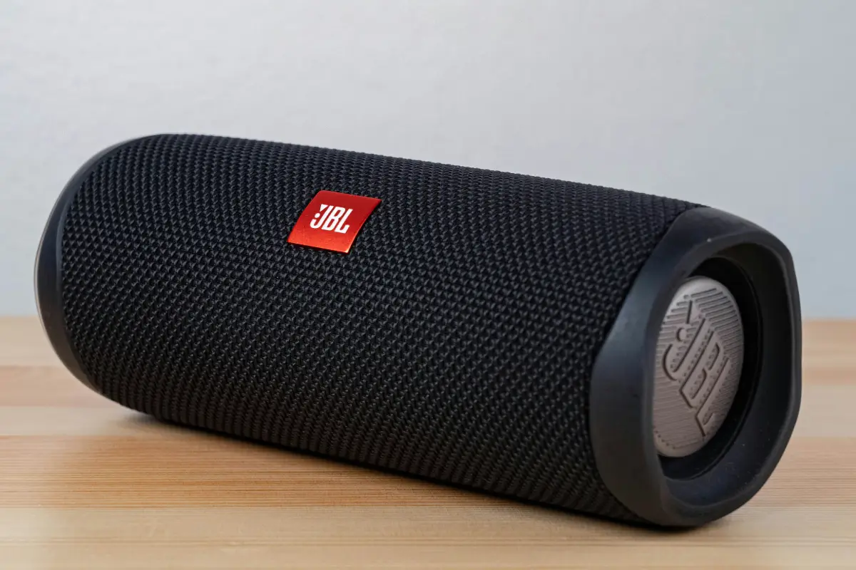 Black portable Bluetooth speaker on wooden surface.