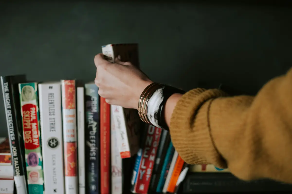 Hand selecting book from a shelf.
