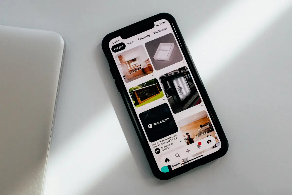Smartphone displaying Pinterest app on white surface.