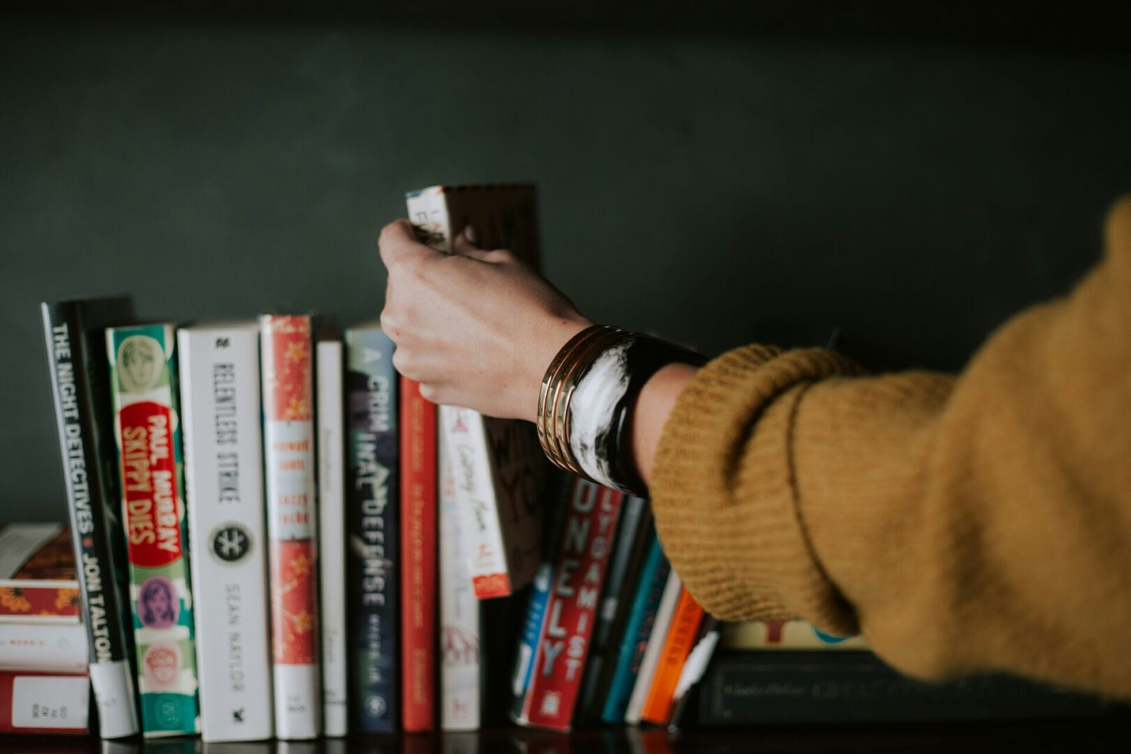 Person selecting a book from shelf.