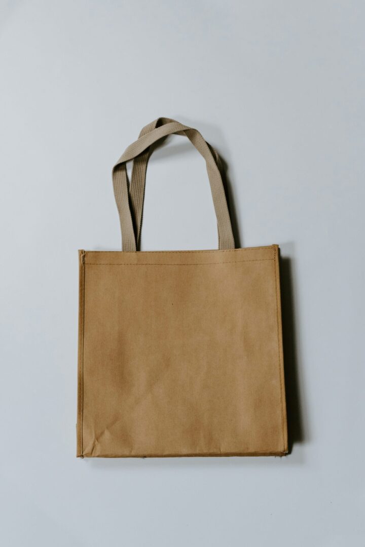 Plain brown tote bag on gray background.