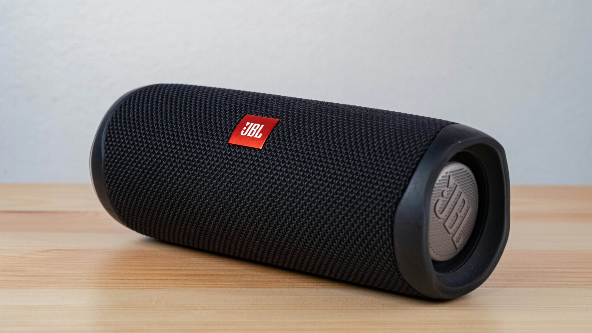 Black portable Bluetooth speaker on wooden surface.