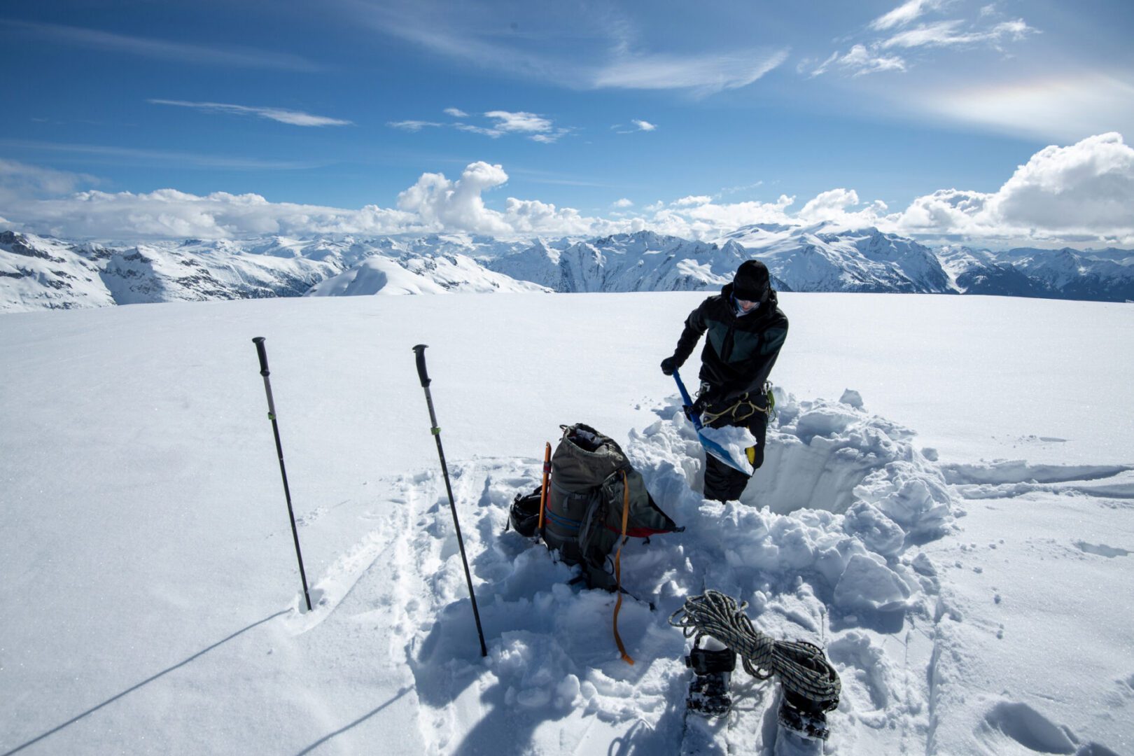 Person digging snow on a mountain summit.