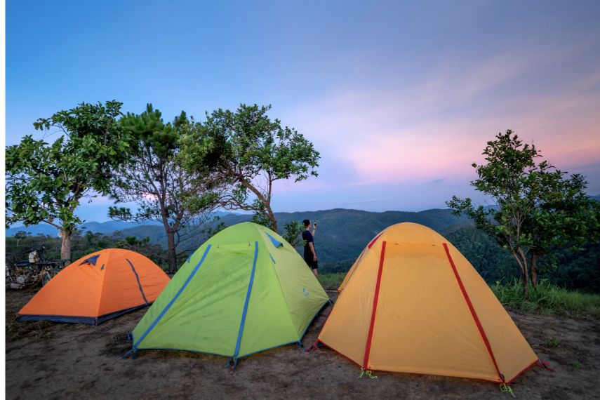 Colorful camping tents on a mountainside at sunset.