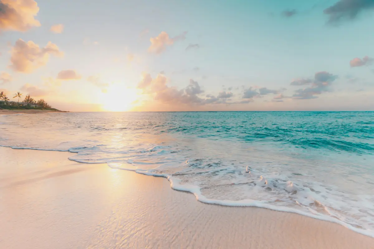 Sunrise over serene beach with gentle waves.