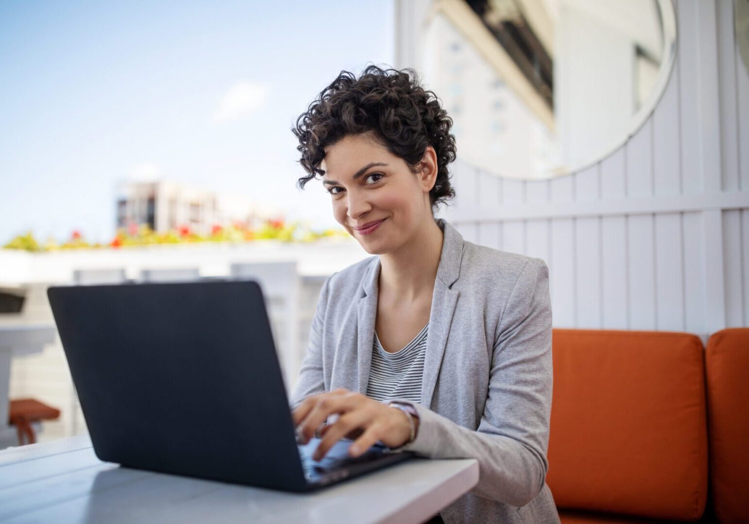 Woman smiling while using a laptop outdoors.
