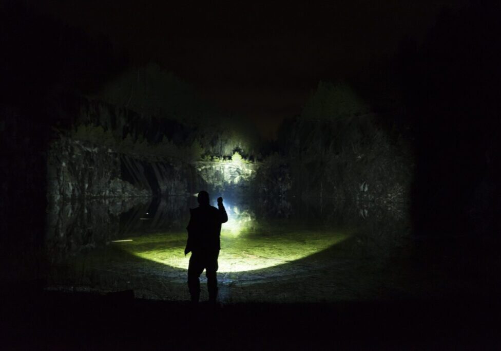 Silhouette of person with flashlight at night.