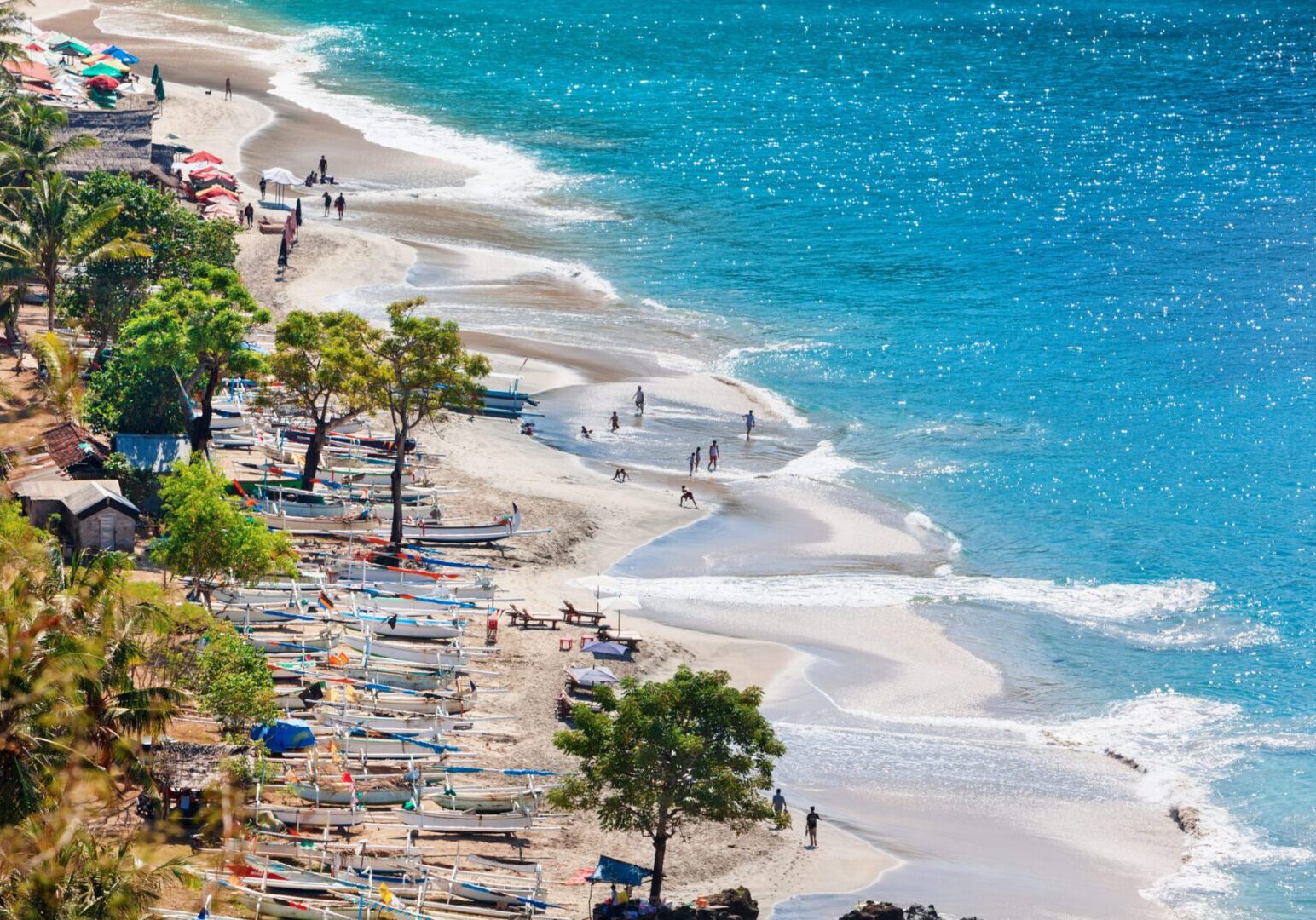 Beach with boats and people enjoying shoreline.