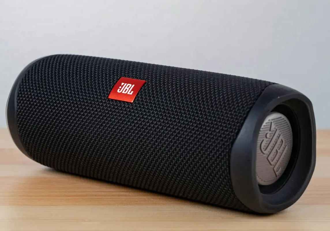 Black portable Bluetooth speaker on wooden surface.