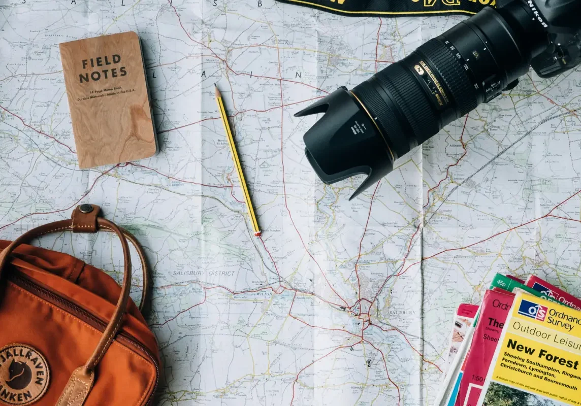 Map with camera, notebook, and bag.