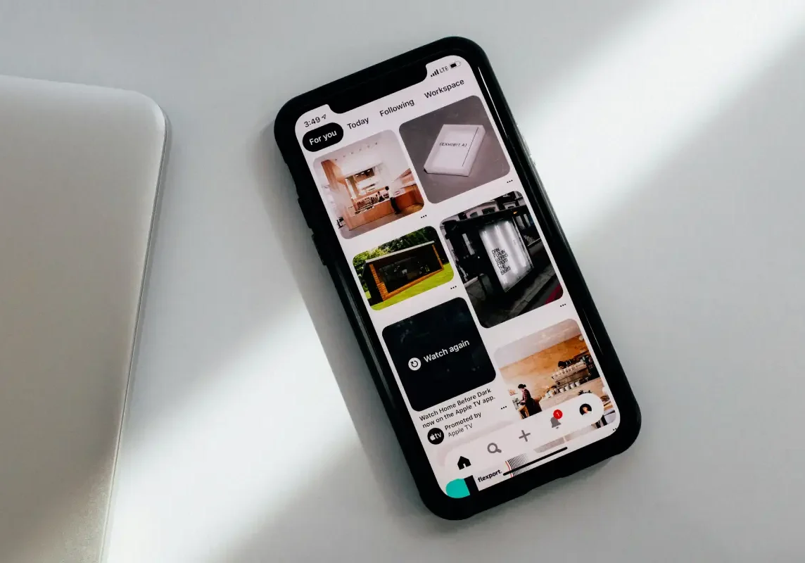 Smartphone displaying Pinterest app on white surface.