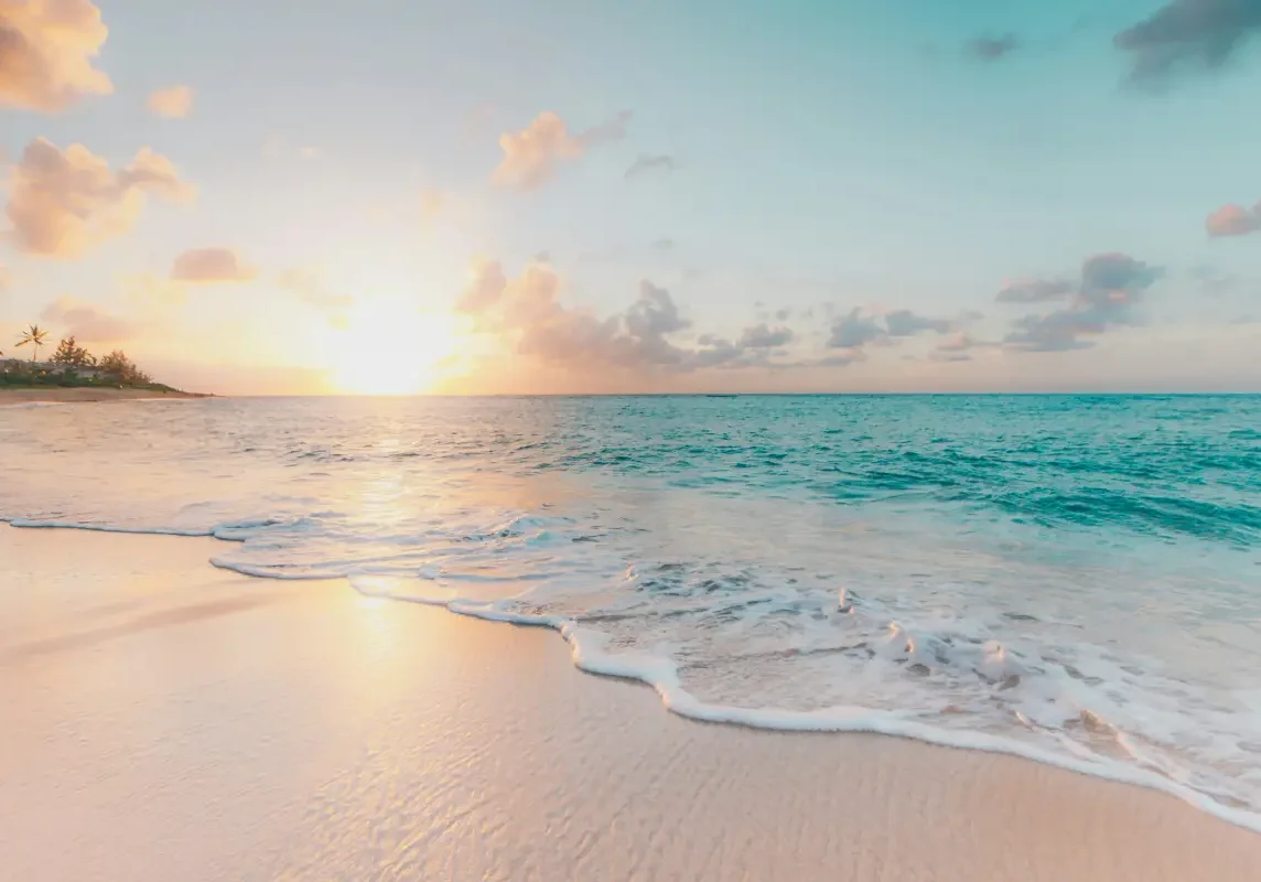 Sunrise over serene beach with gentle waves.