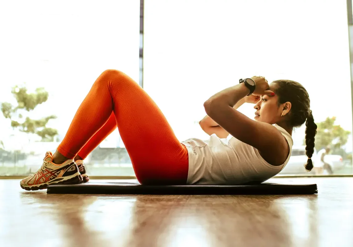 Woman exercising with sit-ups on mat.